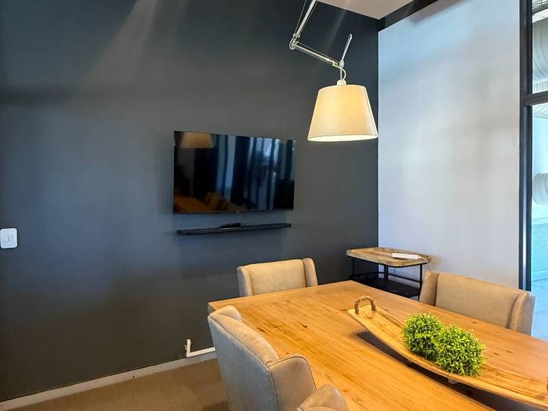 A modern dining area featuring a dark accent wall, recessed lighting, and a stylish pendant light fixture.