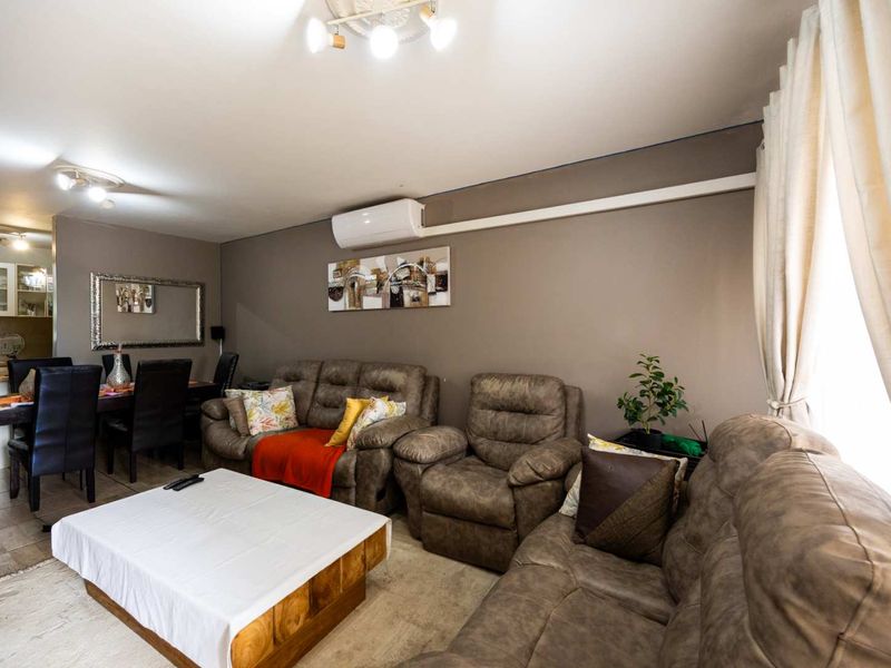 Open-plan living and dining area featuring tiled flooring and a wall-mounted split-system air conditioner.