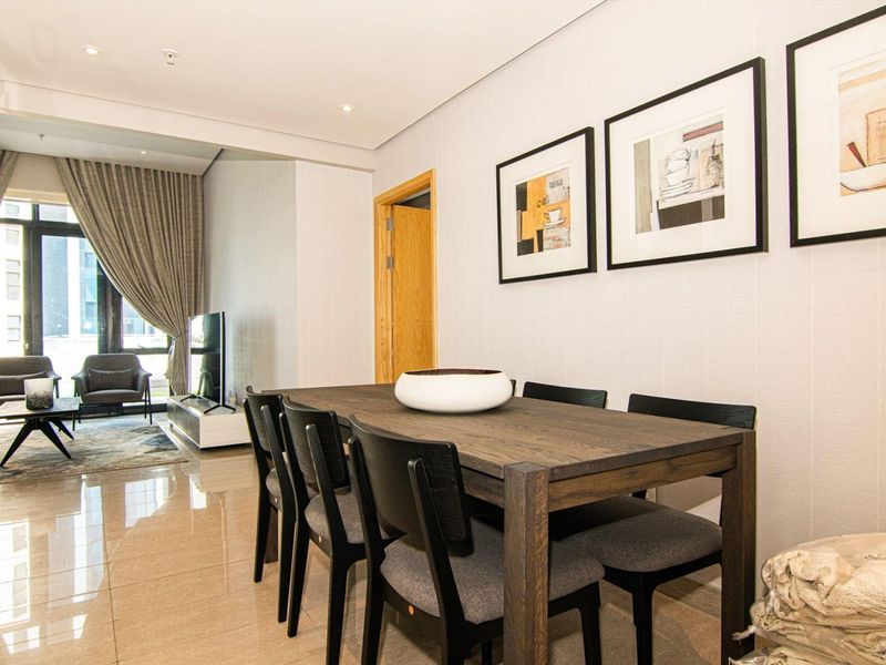 An open-plan living and dining area featuring polished tiled flooring, recessed lighting, and access to a balcony through a large sliding glass door.
