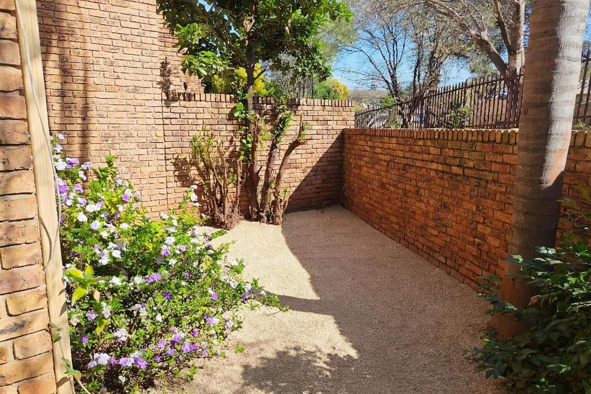 A private rear courtyard area featuring exposed brick boundary walls and low-maintenance gravel ground cover.