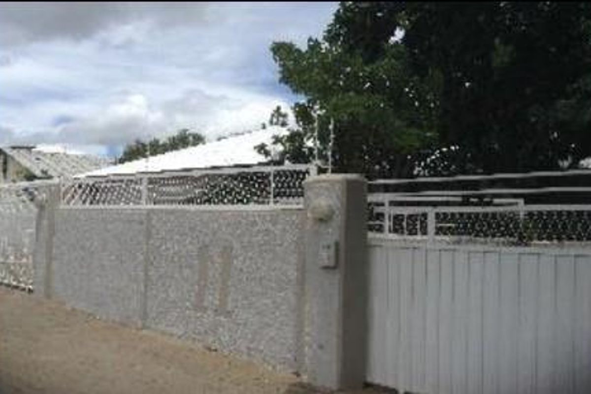 Front exterior view of the office property featuring a secure perimeter wall with electric fencing and a gated entrance.