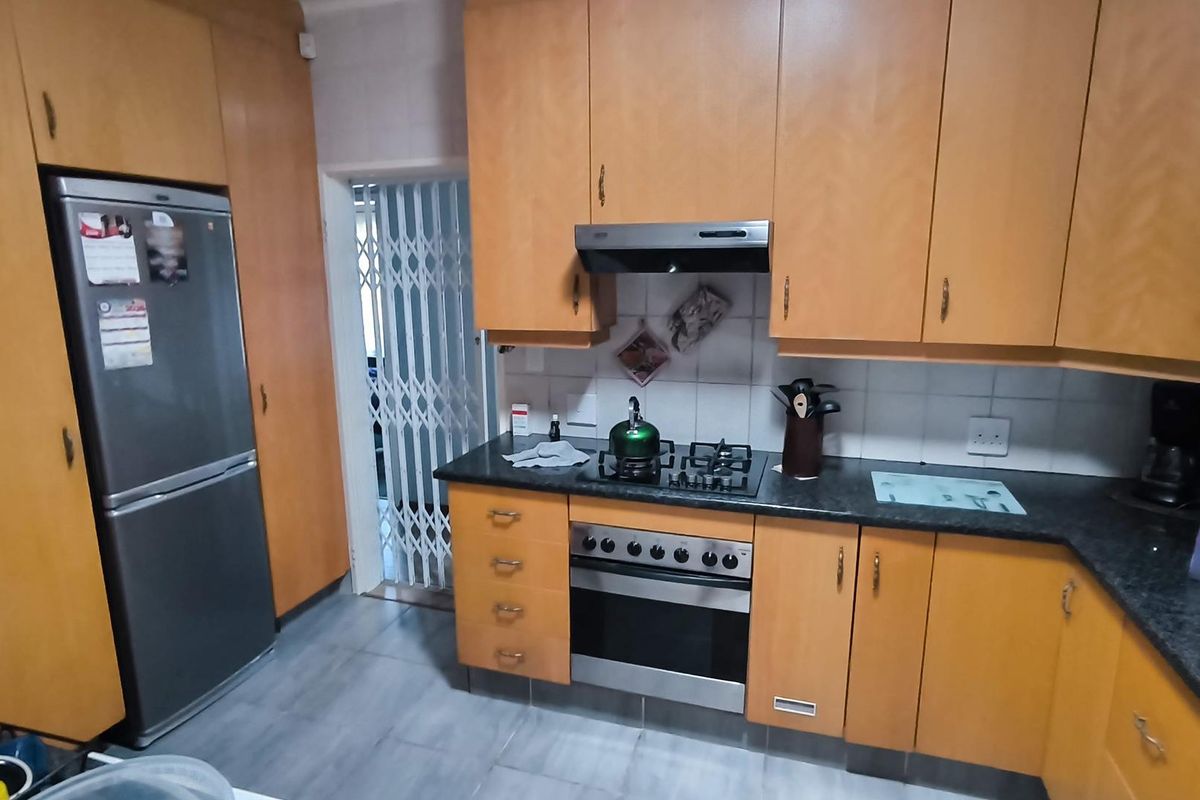 Functional kitchen featuring wooden cabinetry, dark countertops, a built-in oven, gas hob, and an extractor fan.