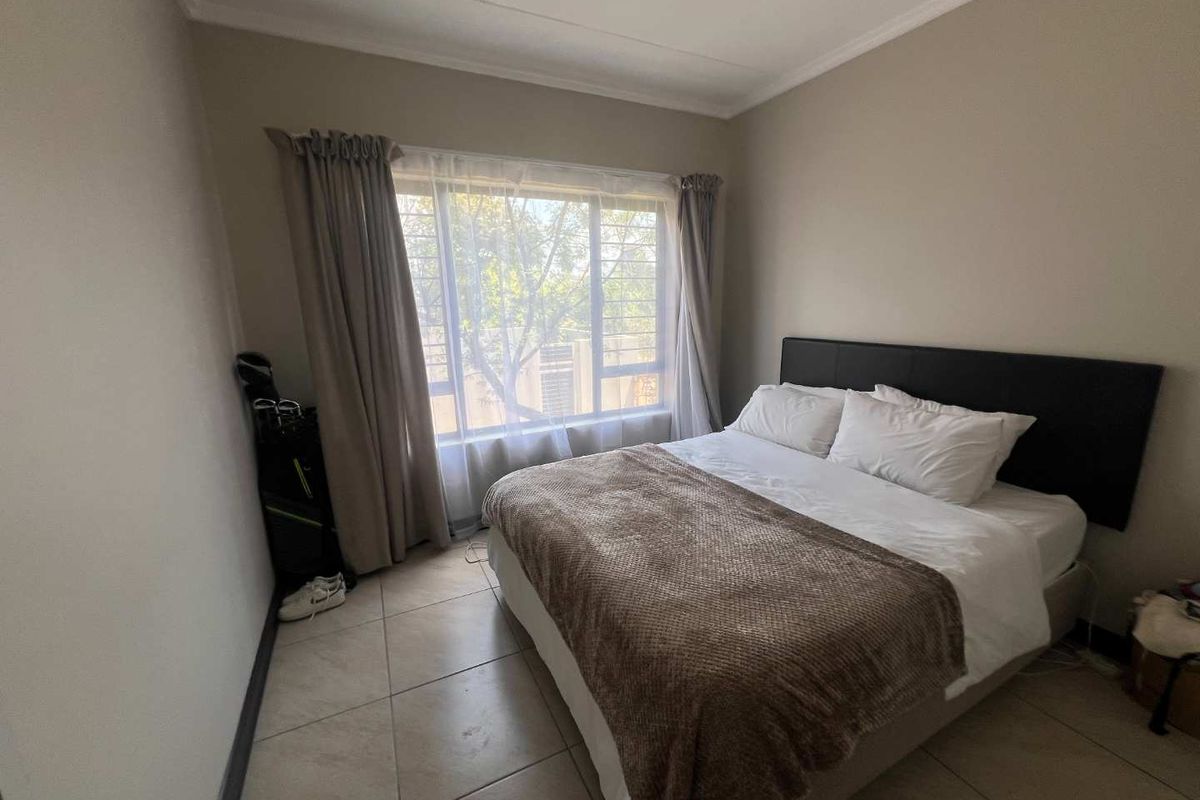 A bedroom featuring tiled flooring and a large window with natural light, providing a neutral and functional living space.
