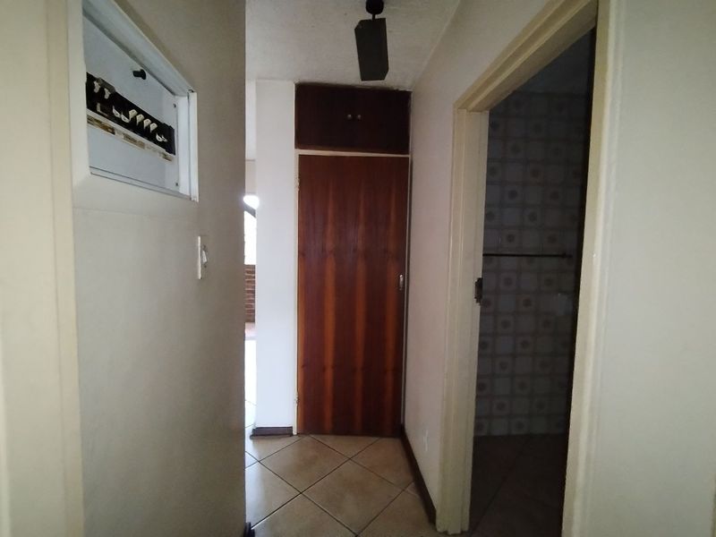 A functional hallway featuring tiled flooring, a built-in storage cupboard, and an accessible electrical distribution board.