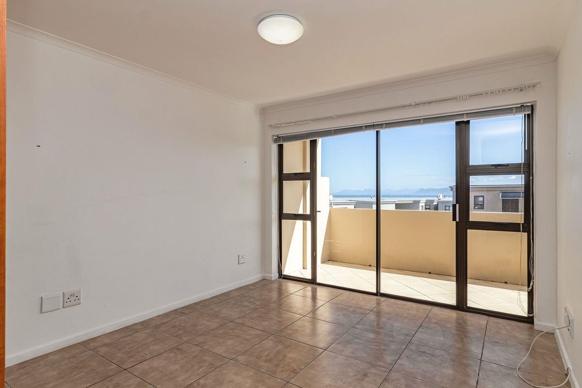 An empty bedroom featuring tiled flooring, a built-in cupboard, and a sliding glass door providing access to a balcony with scenic views.