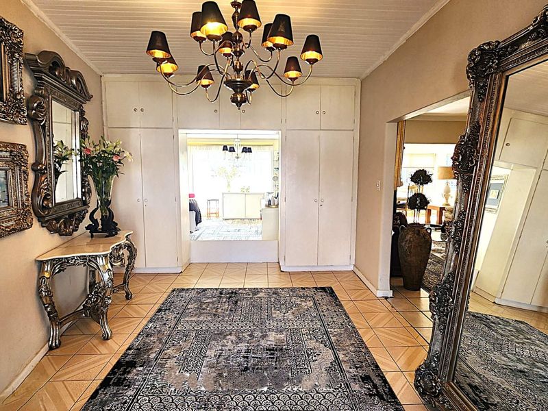 Spacious entrance hall featuring built-in storage cupboards, tiled flooring, and a classic chandelier, providing a welcoming transition into the home's living areas.