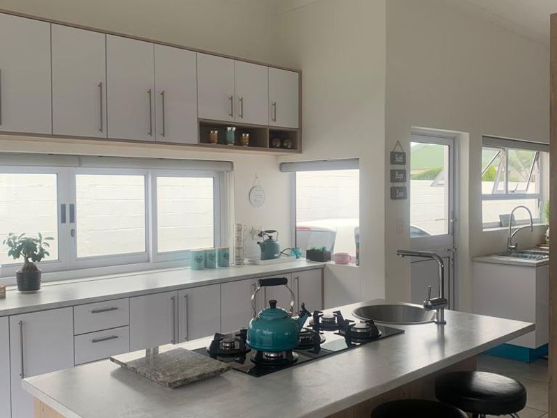 Modern kitchen featuring a central island with a built-in gas cooktop, sleek white cabinetry, and ample counter space with integrated sink fixtures.