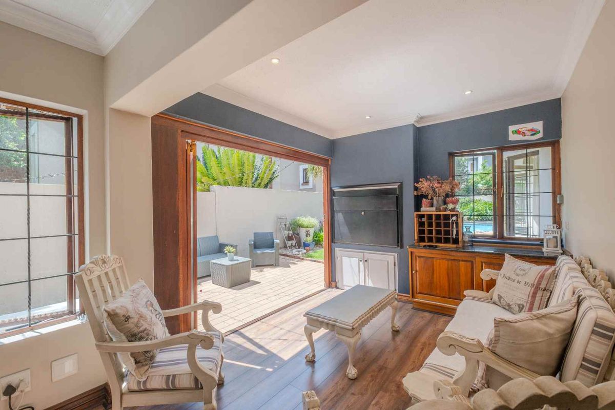 A bright living room featuring wood-look flooring, built-in cabinetry, and large sliding doors that open directly onto a paved patio area.