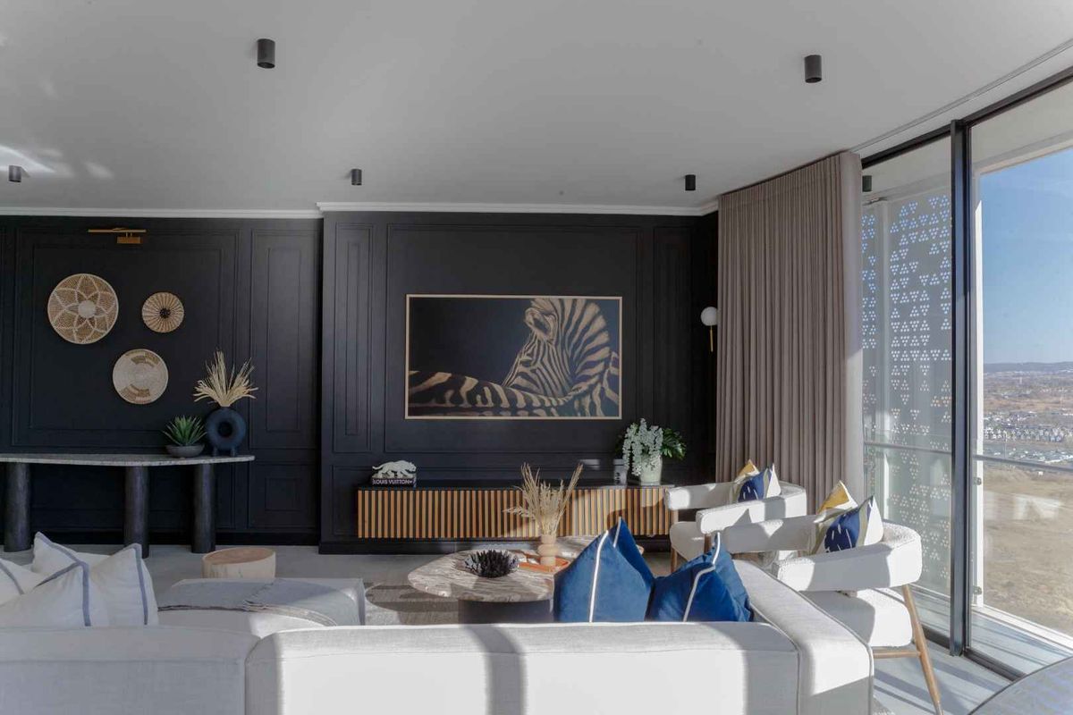 Modern living room featuring elegant dark wall paneling, recessed ceiling lighting, and expansive floor-to-ceiling glass doors offering panoramic views.