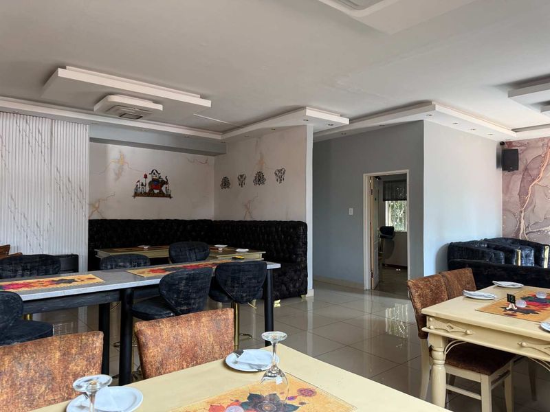 An open-plan dining area featuring tiled flooring, recessed ceiling details with cove lighting, and built-in booth seating, suitable for a restaurant or commercial space.