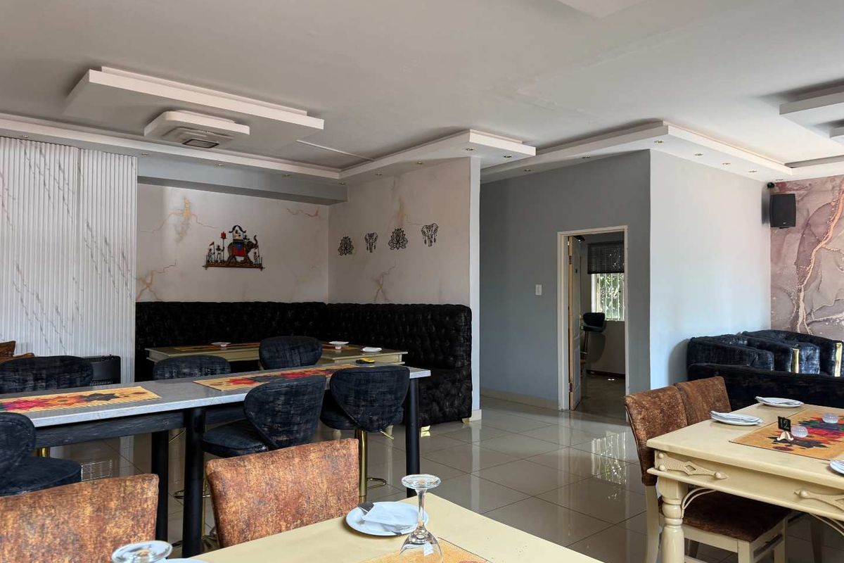 An open-plan dining area featuring tiled flooring, recessed ceiling details with cove lighting, and built-in booth seating, suitable for a restaurant or commercial space.
