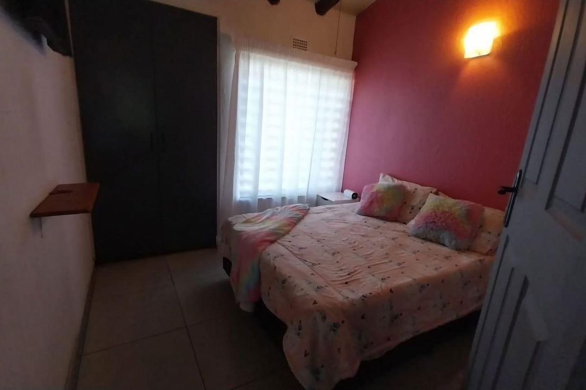 A bedroom featuring tiled flooring, a built-in wardrobe, and a wall-mounted light fixture.