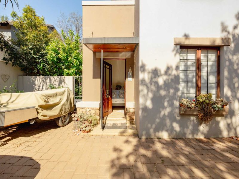 Front entrance of the house featuring a paved driveway, stone-clad accents, a timber front door, and a window planter box.
