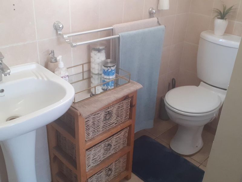 A functional bathroom featuring a pedestal basin, standard toilet, and neutral wall tiling, providing a clean and practical space.