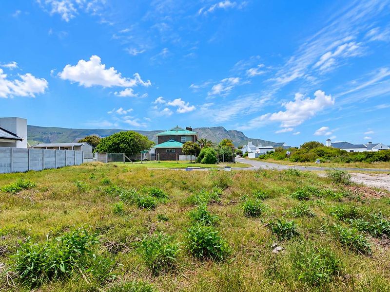 A vacant residential plot featuring a precast concrete boundary wall, offering a clear view of the surrounding neighborhood and mountain landscape.