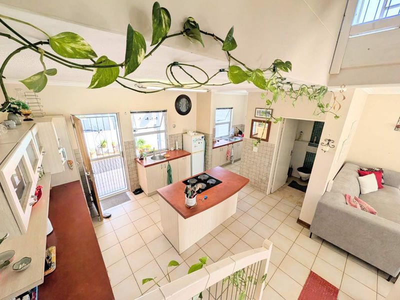 Open-plan living area featuring a functional kitchen with a central island, tiled flooring, and direct access to the exterior.