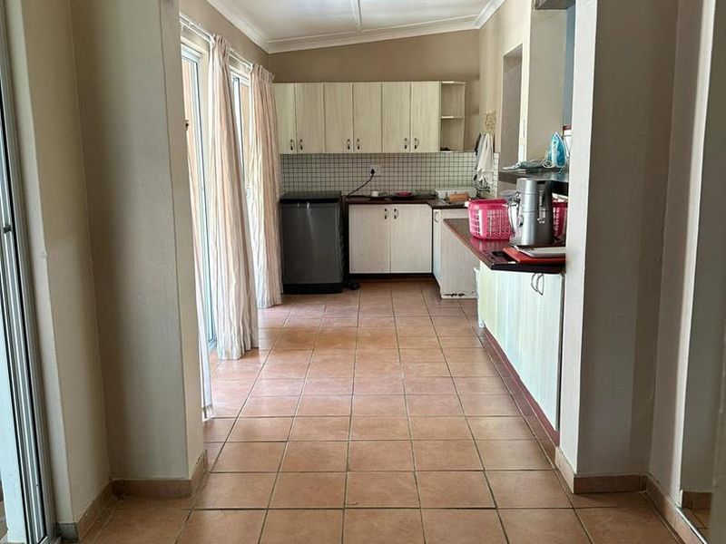 A functional kitchen area featuring tiled flooring, built-in cabinetry, and a tiled backsplash, with direct access to an outdoor space via sliding glass doors.