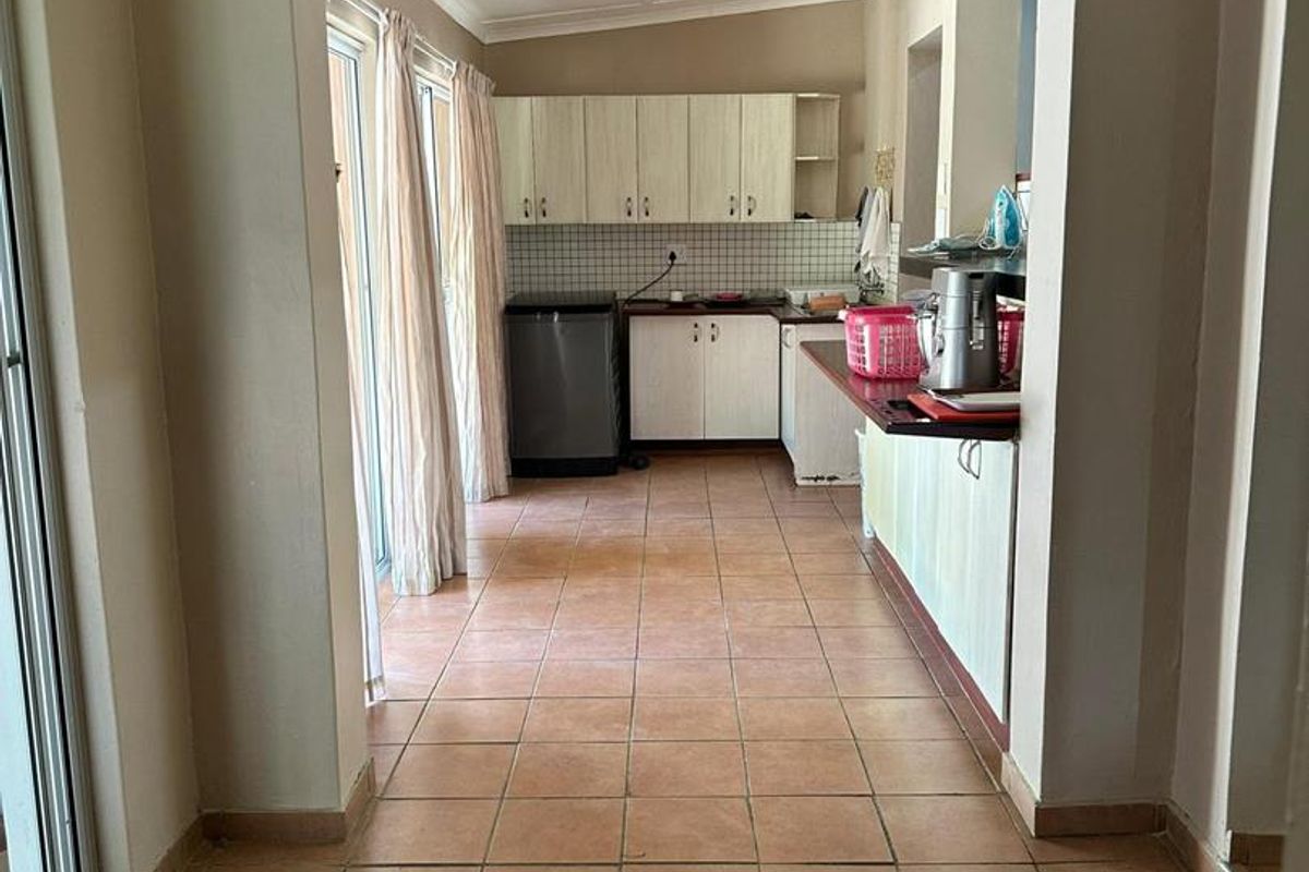 A functional kitchen area featuring tiled flooring, built-in cabinetry, and a tiled backsplash, with direct access to an outdoor space via sliding glass doors.