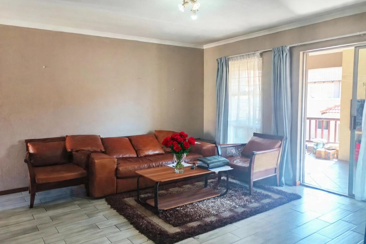 A living room featuring tiled flooring, a coved ceiling, and a sliding glass door providing access to an outdoor patio area.