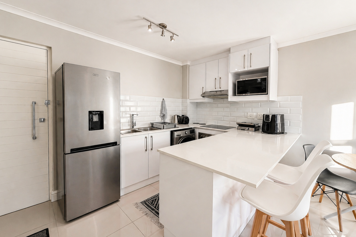 Modern kitchen featuring white cabinetry, subway tile backsplash, quartz countertops, and integrated appliances, including a breakfast bar area.