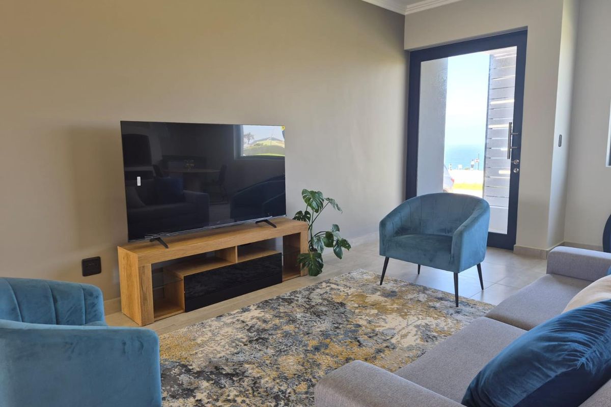 A bright living room featuring neutral walls, tiled flooring, and a glass door providing natural light and access to the outdoors.