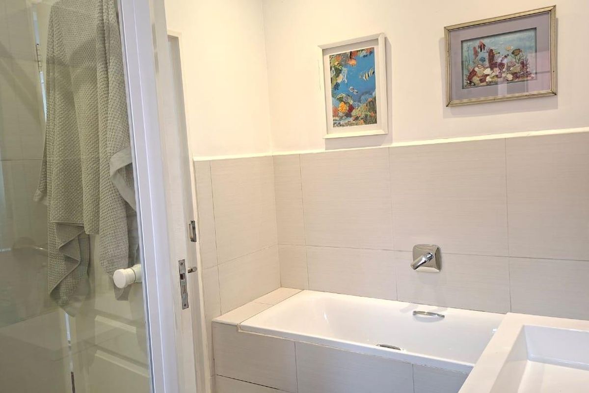 A functional bathroom featuring a built-in bathtub, a separate glass-enclosed shower, and a modern vanity basin with wall-mounted fixtures.