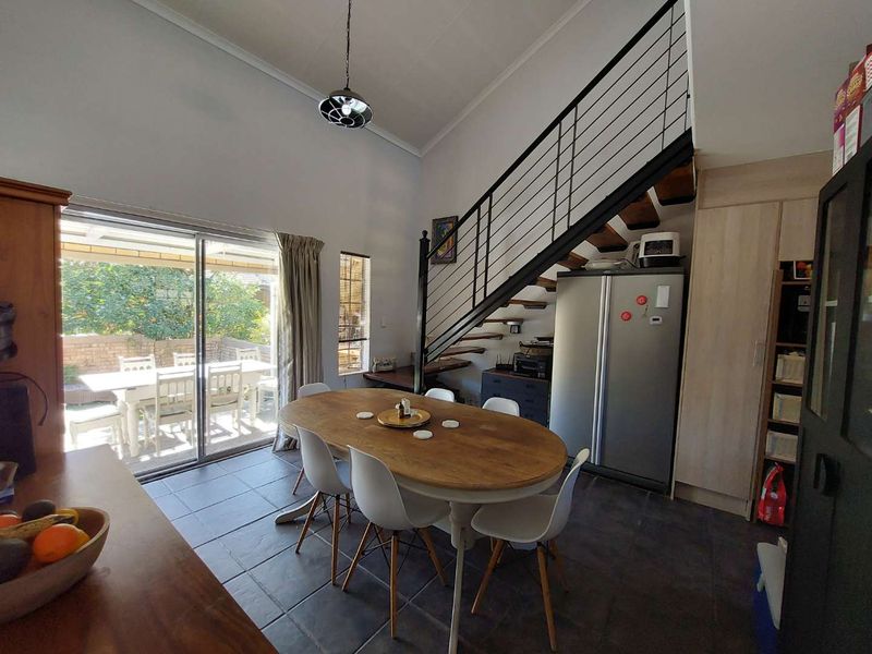 Open-plan living and dining area featuring tiled floors, a modern staircase with metal balustrades, and large sliding doors leading to an outdoor patio.