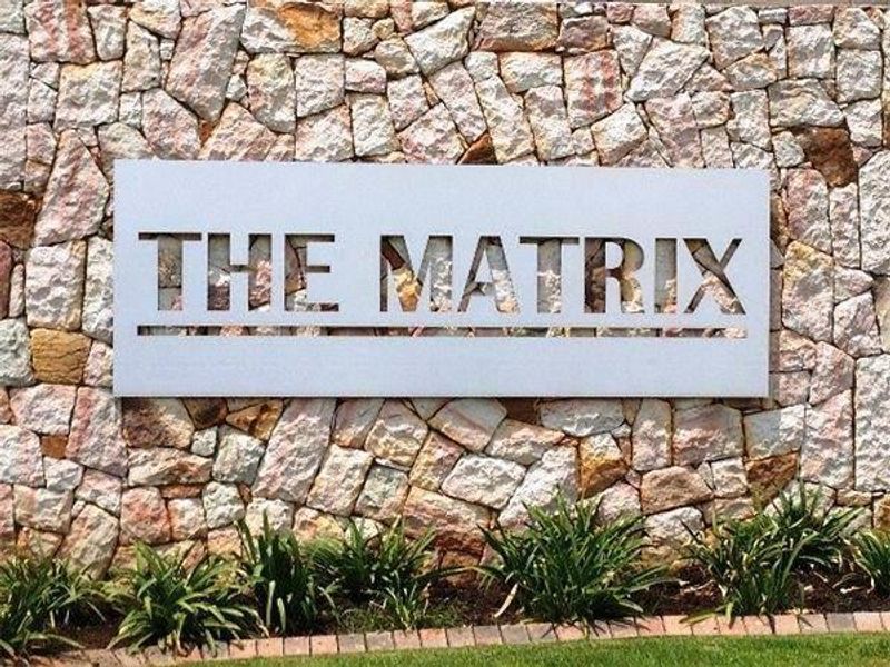 A feature stone wall displaying the property name signage at the entrance of the apartment complex.
