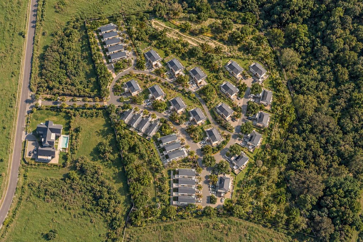 Aerial view of a well-planned residential estate featuring multiple housing units, internal road infrastructure, and extensive landscaped green spaces.