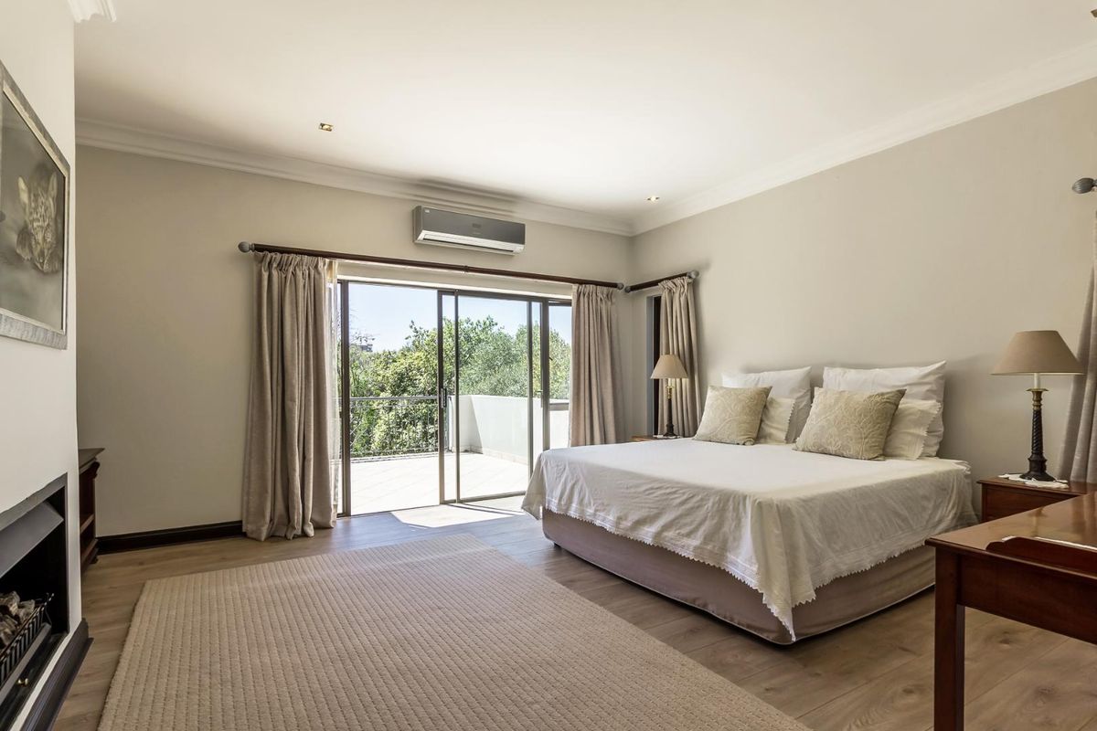 Spacious bedroom featuring light wood-look flooring, a built-in air conditioning unit, and large sliding glass doors opening onto a private balcony.