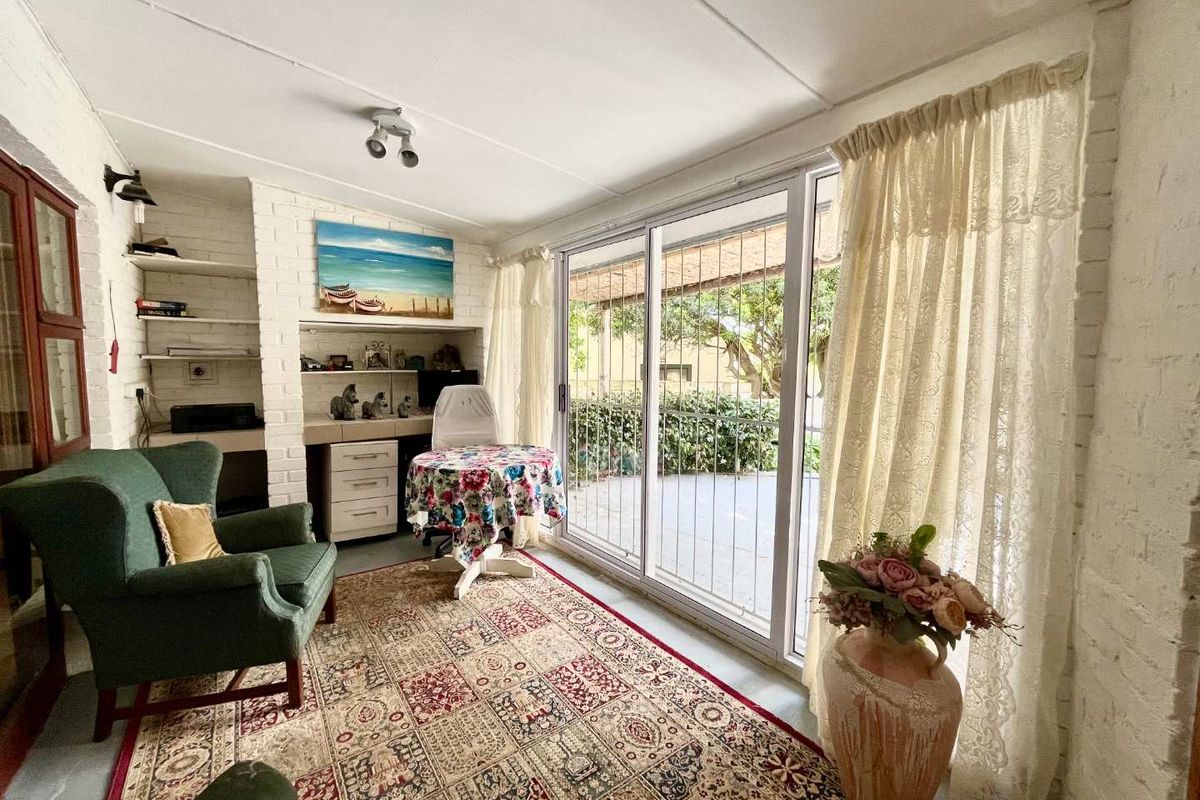 A sunlit living area featuring painted brick walls, built-in shelving, and large sliding glass doors that provide direct access to the outdoor patio.