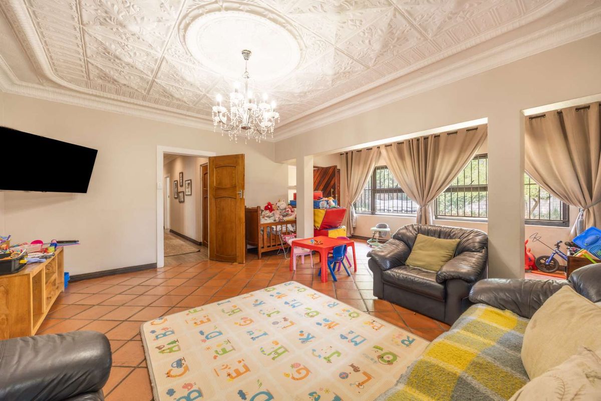 Spacious living area featuring a decorative pressed metal ceiling with a central chandelier and classic terracotta floor tiles.