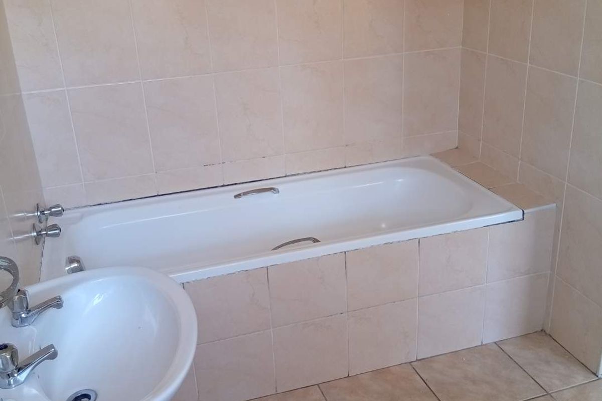A functional bathroom featuring a pedestal basin and a built-in bathtub with tiled surround and splashback.