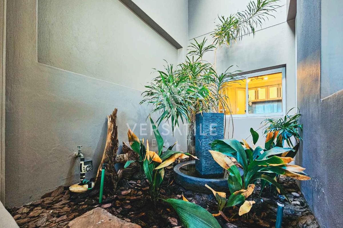 A private internal courtyard or light well featuring a decorative water feature, stone mulch, and access to the interior living space.
