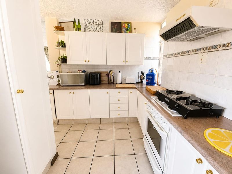 A functional kitchen featuring white cabinetry, tiled backsplash, gas hob, and built-in oven, offering a practical layout with ceramic tile flooring.