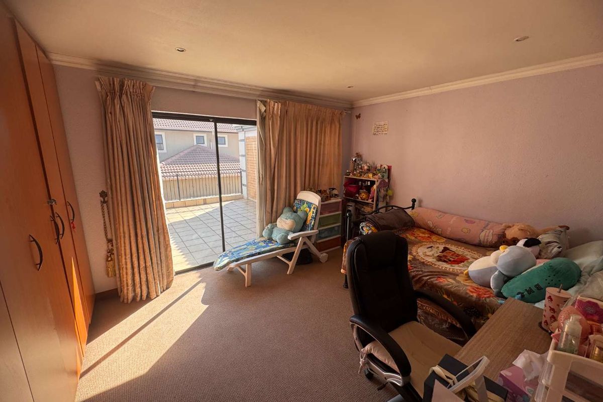A bedroom featuring built-in cupboards, carpeted flooring, and a sliding glass door providing access to an outdoor patio area.