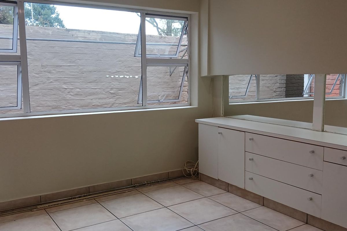 A bedroom featuring tiled flooring, built-in cabinetry with integrated mirror, and large windows overlooking a rear exterior wall.