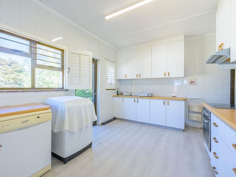 Functional kitchen featuring white cabinetry, wood-look countertops, integrated appliances, and tiled walls with natural light from the side window.