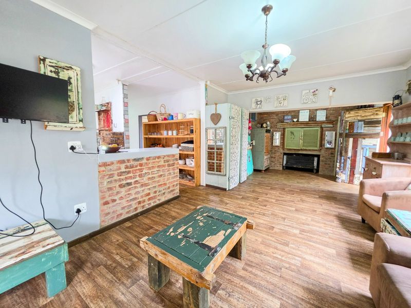 Open plan living area featuring exposed brick accents, laminate flooring, and a central breakfast bar, offering a rustic aesthetic with potential for modern updates.