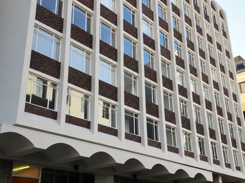 Exterior view of Senator Park apartment building featuring a distinctive arched facade, brick detailing, and ground-level entrance with security access.