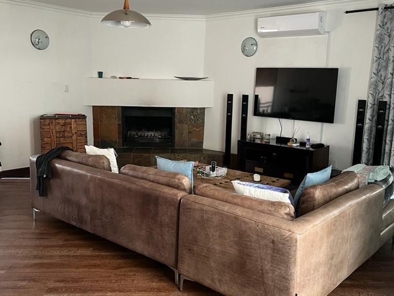 Spacious living room featuring a fireplace with slate surround, split-system air conditioning, and a combination of laminate and slate tile flooring.