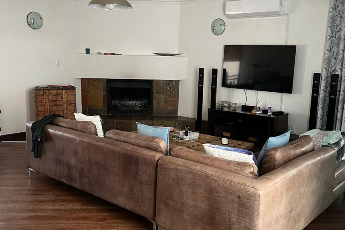 Spacious living room featuring a fireplace with slate surround, split-system air conditioning, and a combination of laminate and slate tile flooring.