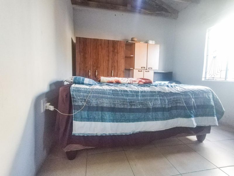 A bedroom featuring tiled flooring, exposed ceiling beams, and built-in wardrobe storage, requiring cosmetic updates to improve the overall finish.