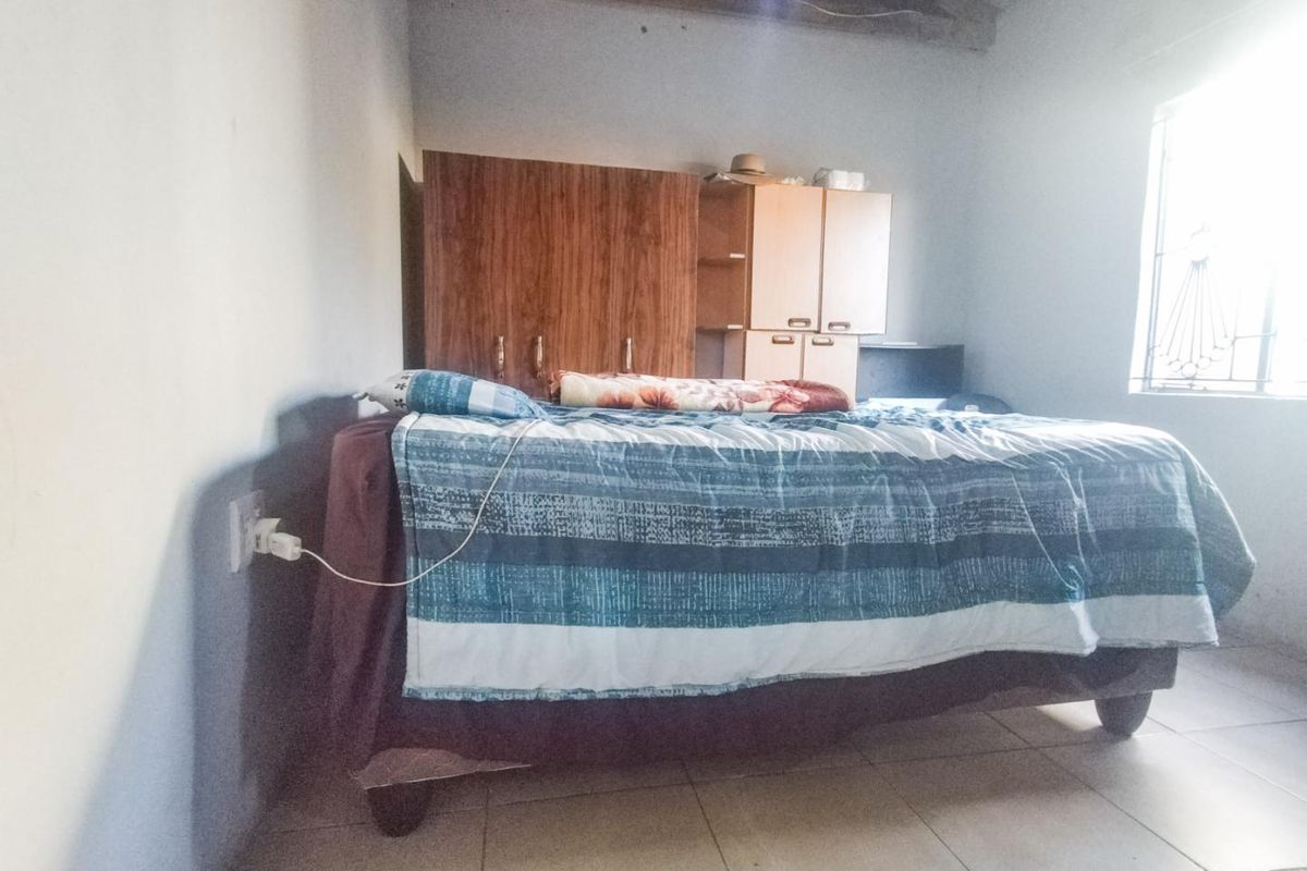 A bedroom featuring tiled flooring, exposed ceiling beams, and built-in wardrobe storage, requiring cosmetic updates to improve the overall finish.