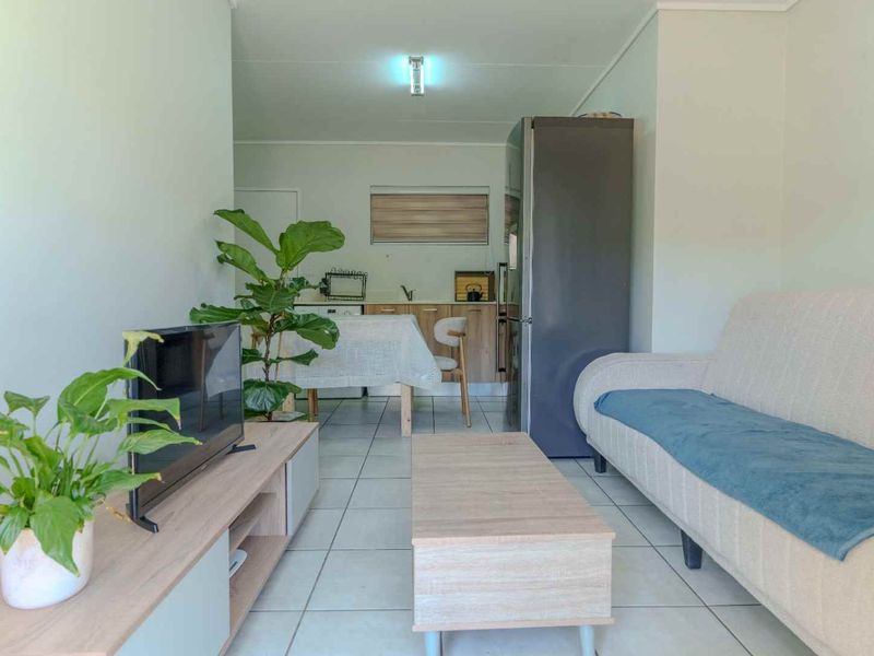Open-plan living area featuring tiled flooring and a functional kitchen space, providing a versatile layout for comfortable apartment living.
