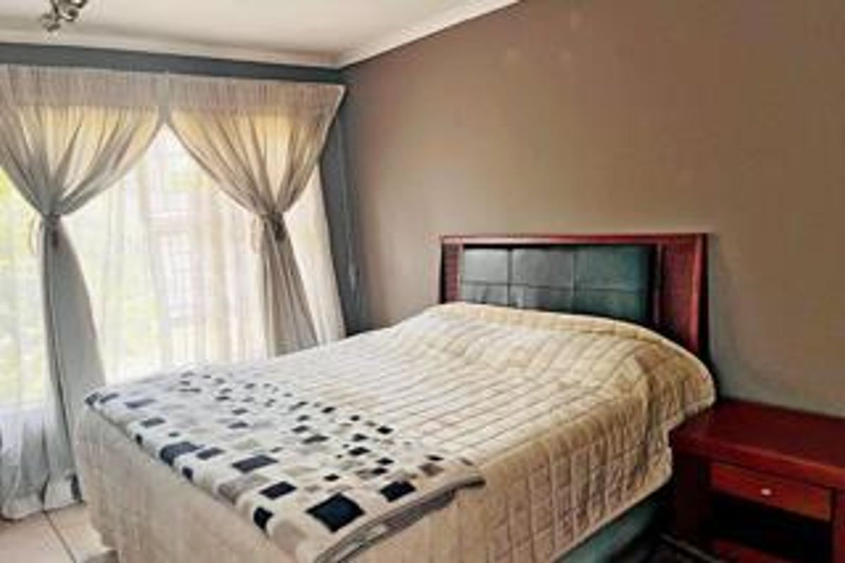 A bedroom featuring tiled flooring and a sliding glass door providing natural light.