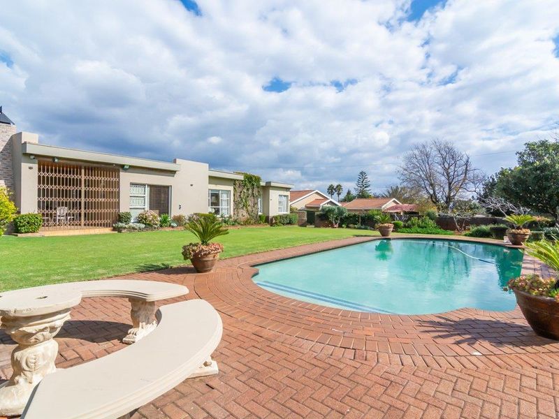 A spacious rear garden featuring a swimming pool, brick-paved patio area, and well-maintained lawn, providing an ideal space for outdoor relaxation and entertainment.