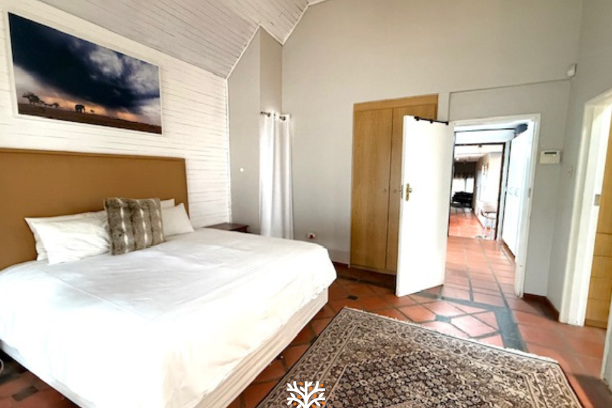 Spacious bedroom featuring high vaulted ceilings, built-in wooden cabinetry, and traditional terracotta floor tiles, offering a bright and airy atmosphere.