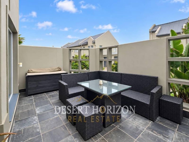 A private outdoor patio area featuring dark tiled flooring and decorative concrete screen walls, providing a comfortable space for outdoor relaxation.