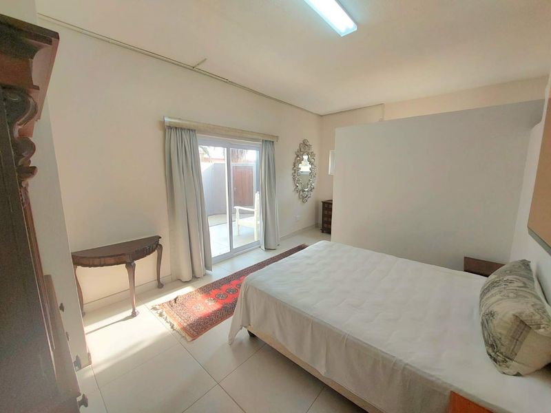 A bedroom featuring tiled flooring and a sliding glass door providing access to an outdoor area, with a partition wall creating a semi-private space.
